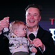 Elon Musk holds his son X Æ A-12's hand on stage at an event.
